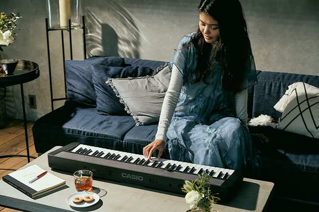 Girl Playing Black Casio CT-S1 Keyboard sitting on couch