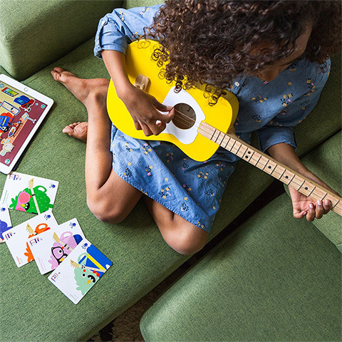 child playing Loog guitar with accessories
