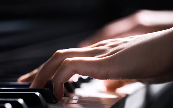 Hands playing piano keys close up 